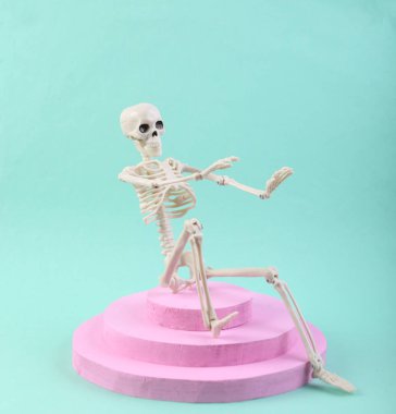 Mavi arka planda iskeleti olan pembe bir podyum. Asgari tasarımda soyut kompozisyon.