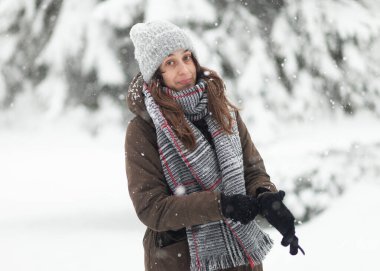 Sıcak elbiseli bir kadın, kışın karlı havada eldiven giyiyor.
