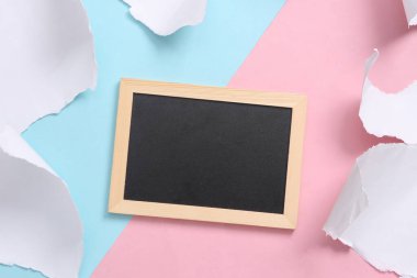 Pastel color trend. Empty blackboard on a blue-pink background with torn paper. Concept art. Creative layout. Minimalism. Top view