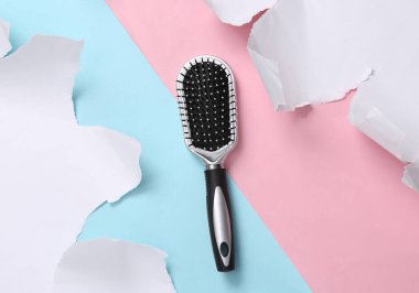 Hair brush on a blue-pink background with torn paper. Concept art. Pastel color trend. Creative layout. Minimalism. Top view