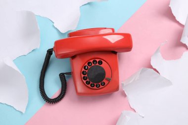 Retro rotary phone on blue-pink background with torn paper. Concept art. Pastel color trend. Creative layout. Minimalism. Top view