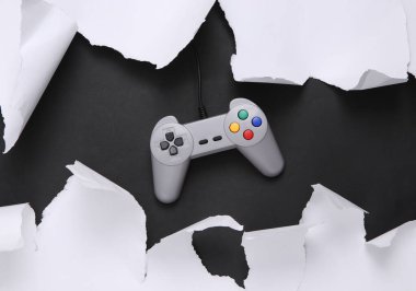 Retro gamepad on black background with white torn paper. Concept art. Minimalism. Top view