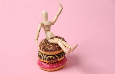 Wooden puppet on a stack of donuts