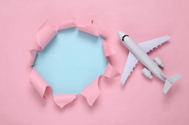 Torn hole and air plane on a blue-pink pastel background. Travel Concept. Copy space. Pastel color trend. Minimalism