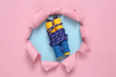 Skipping rope through torn hole on blue-pink pastel background. Concept art. Pastel color trend. Minimalism