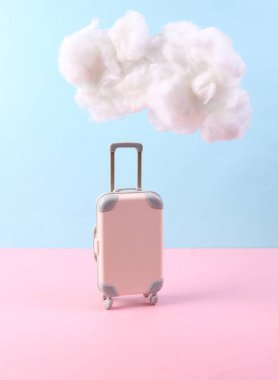 Pembe arka planda yumuşak bulutlu seyahat valizleri. Yaratıcı bir fikir. Minimum seyahat konsepti. Pastel renk eğilimi