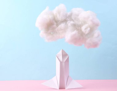 Uzay origami mekiği ve mavi pembe pastel arka planda bulut. Başlangıç, rüya kavramı. Uzayın fethi. Yaratıcı fikir 
