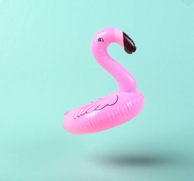 Mavi arka planda şişme flamingo yükseliyor. Minimalizm. 3B fotoğraf