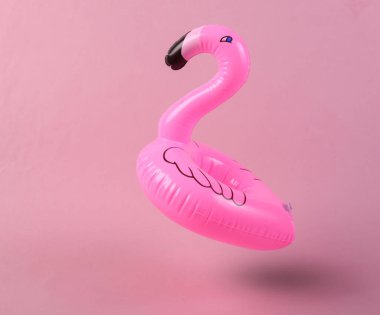 Pembe arka planda şişme flamingo yükseliyor. Minimalizm. 3B fotoğraf