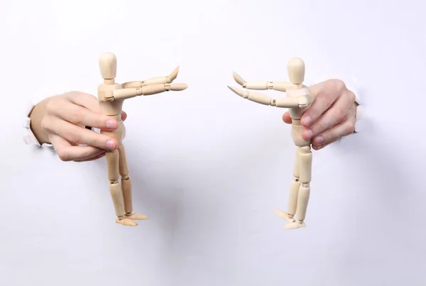 Γυναικεία Χέρια Που Κρατούν Ξύλινες Μαριονέτες Μέσα Από Σχισμένο Λευκό — Φωτογραφία Αρχείου