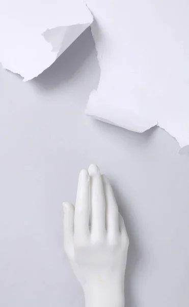 灰色の背景に白い手と白い引き裂かれた紙のシート コンセプトアート ミニマリズム トップ表示 — ストック写真