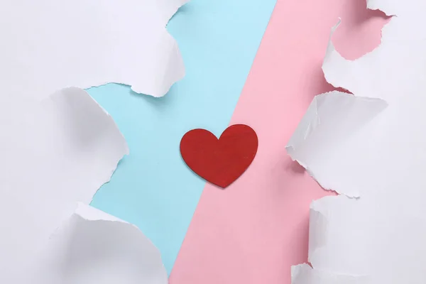 Love concept. Red heart on blue-pink background with torn paper. Concept art. Pastel color trend. Creative layout. Minimalism. Top view