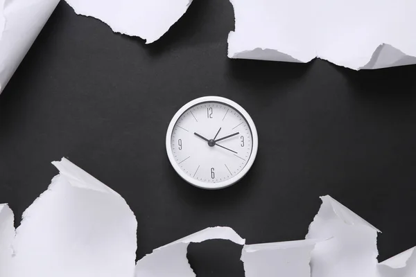 Clock on black background with white torn paper. Concept art. Minimalism. Top view