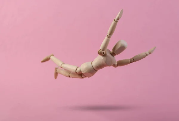 ピンクの背景に木製の人形を落下 — ストック写真