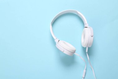 Mavi arka planda beyaz renkli stereo kulaklıklar. Minimalist müzik hala hayat, müzik aşığı. Üst Manzara. Düz yatıyordu