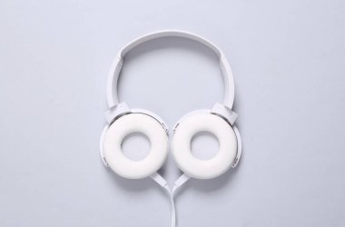 Gri arka planda beyaz renkli stereo kulaklıklar. Minimalist müzik hala hayat, müzik aşığı. Üst Manzara. Düz yatıyordu