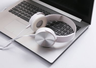 Kulaklıklı, gri arka planda bir laptop. Müzik konsepti
