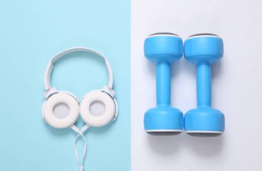 Mavi beyaz arka planda dambıllar ve kulaklıklar. Spor aksesuarları. Üst görünüm