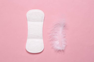 Kadın hijyeni konsepti. Adet öncesi jinekolojik yumuşak ped ve pembe arka planda tüy