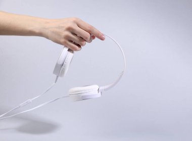 Kadın eli delikleri Gri arka planda havalı stereo kulaklıklar