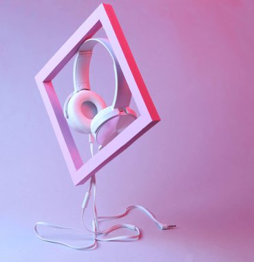 Pembe çerçeveli beyaz stereo kulaklıklar. Pembe neon renkte. Modern minimalist müzikal natürmort