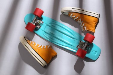 Minimalist modern natürmort. Bozuk para panosu ve gri arka planda uzun çizgili moda gölgeleri olan spor ayakkabıları. Üst görünüm