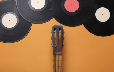 Akustik gitar yaka, kahverengi arka planda vinil plak. Müzik konsepti. Minimalizm. Üst Manzara. Düz yatıyordu