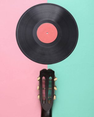 Akustik gitar yaka, pembe mavi arka planda vinil plak. Müzik konsepti. Minimalizm. Üst Manzara. Düz yatıyordu