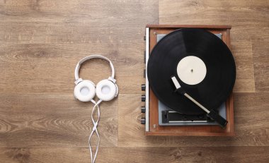 Stereo kulaklıklar ve tahta zeminde retro vinil plak çalar. Müzik konsepti. Üst Manzara. Düz yatıyordu