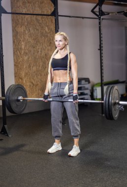 Kaslı kadın, modern işlevsel spor salonunda ağırlık kaldırma hareketini yapıyor.