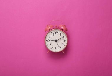 Pembe arka planda pembe çalar saat. Minimalizm. Üst Manzara. Düz yatıyordu