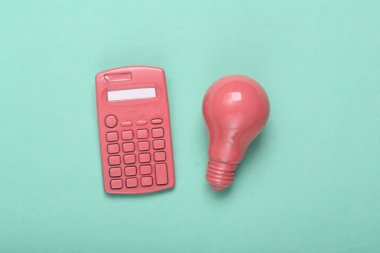 Pembe hesap makinesi ve pembe mavi arka planda ampul. Minimalizm. Yaratıcı düzen. Yeni bir fikir. Üst Manzara. Düz yatıyordu