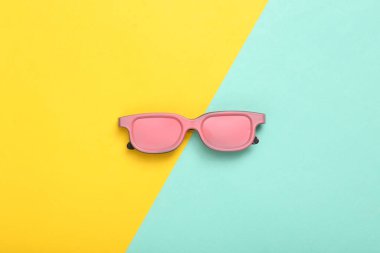 Mavi sarı arka planda pembe güneş gözlüğü. Üst Manzara. Düz yatıyordu. Sanat kavramı. Minimalizm 