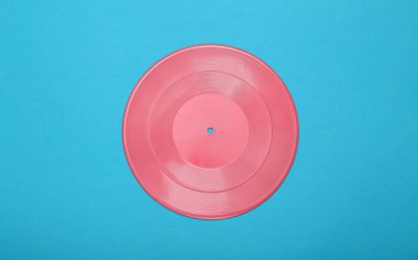Yaratıcı müzik düzeni. Mavi arka planda pembe vinil plak. Minimalizm. Düz yatıyordu. Üst görünüm.