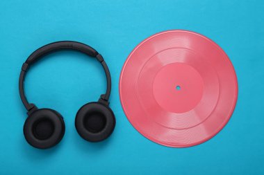 Yaratıcı müzik düzeni. Pembe plak kaydı ve mavi arka planda kulaklık. Minimalizm. Düz yatıyordu. Üst görünüm