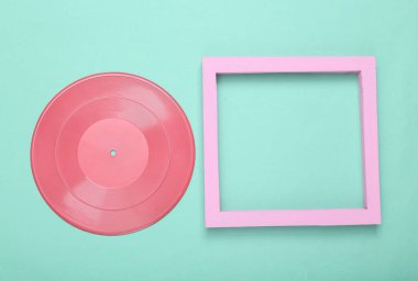 Yaratıcı müzik düzeni. Nane mavisi arka planda boş çerçeveli pembe vinil plak. Minimalizm. Düz yatıyordu. Üst Manzara. Boşluğu kopyala