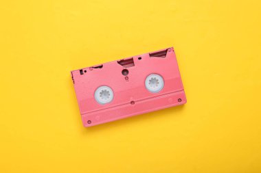 Sarı arka planda pembe video kaset. Minimalizm. Düz yatıyordu. Üst görünüm.