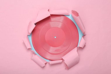 Yaratıcı müzik düzeni. Pembe plak, yırtılmış pembe mavi kağıt deliğinden geçiyor. Pastel renk eğilimi. Yeni bir fikir. Minimalizm. Sanat kavramı. Düz yatıyordu. Üst görünüm.