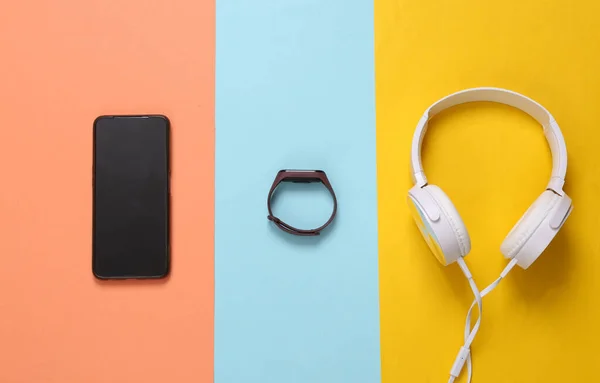 Modern gadgets. Smartphone, headphones and smart bracelet on a colored background. Top view
