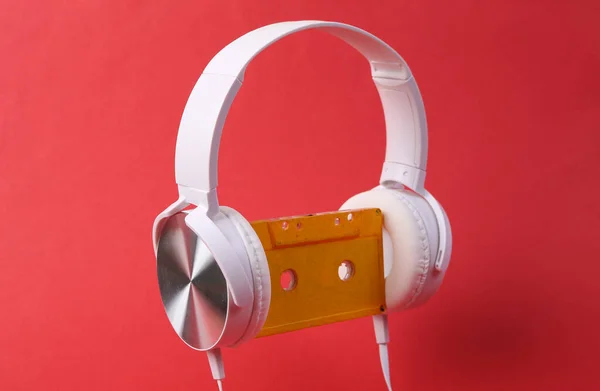 红色背景的带复古盒式磁带的白色立体声耳机 80年代音乐概念 — 图库照片