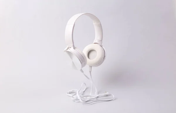 灰色の背景に白いケーブルステレオヘッドフォンをレベリング — ストック写真
