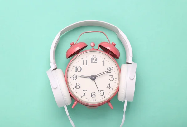 蓝色背景的带粉色闹钟的立体声耳机 简约主义音乐概念 创意布局 新鲜想法 — 图库照片