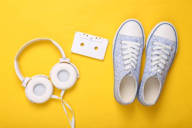 Beyaz ses kaseti, kulaklıklar ve sarı arka planda spor ayakkabıları. Üst Manzara. Düz yatıyordu
