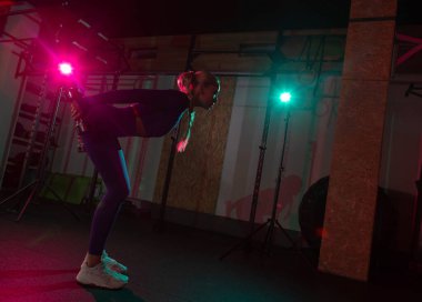 Spor salonunda elinde dambıllarla spor yapan zayıf, genç, formda bir kadın. Spor, spor, yaşam tarzı konsepti