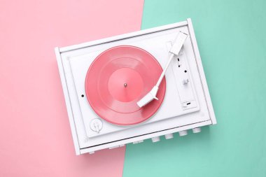 Pembe arka planda turntable vinil plak çalar. DJ 'in müziği karıştırıp çalması için ses teknolojisi. Beyaz plak plağı. Minimalizm. Düz yatıyordu. Üst görünüm