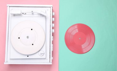 Pembe arka planda turntable vinil plak çalar. DJ 'in müziği karıştırıp çalması için ses teknolojisi. Beyaz plak plağı. Minimalizm. Düz yatıyordu. Üst görünüm