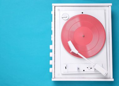 Turntable vinil müzik çalar mavi arkaplanda. DJ 'in müziği karıştırıp çalması için ses teknolojisi. Pembe plaklı beyaz vinil plak. Minimalizm. Düz yatıyordu. Üst Manzara. Boşluğu kopyala