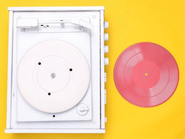 Turntable vinil plak çalar sarı arka planda. DJ 'in müziği karıştırıp çalması için ses teknolojisi. Pembe plaklı beyaz vinil plak. Minimalizm. Düz yatıyordu. Üst görünüm.