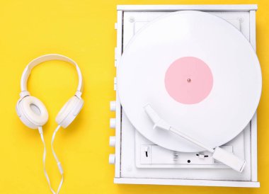 Turntable plakçalar ve sarı arka planda kulaklıklar. DJ 'in müziği karıştırıp çalması için ses teknolojisi. Beyaz plak plağı. Minimalizm. Düz yatıyordu. Üst görünüm.