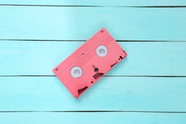 Minimalizmin yaratıcı düzeni. Mavi ahşap arka planda pembe video kaset. Minimalizm. Üst Manzara. Düz yatıyordu